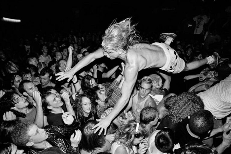 Fã surfando na multidão durante show nos Anos Dourados do Grunge.