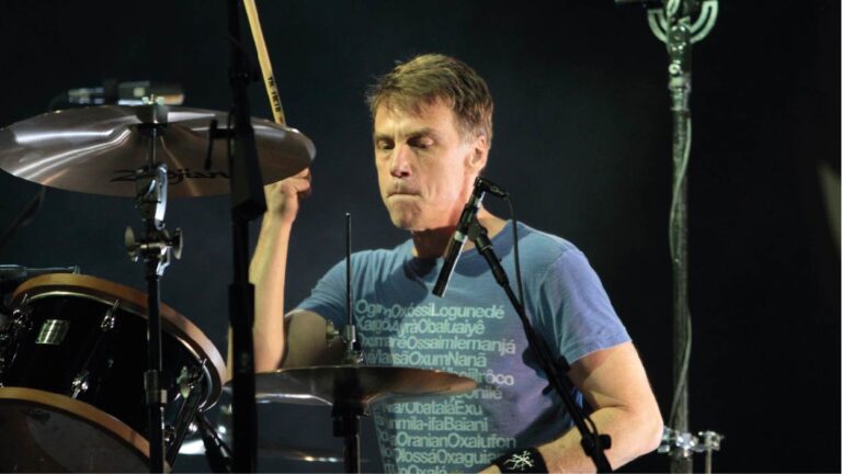 Matt Cameron tocando bateria em show do Pearl Jam, concentrado durante performance ao vivo com iluminação de palco destacando o baterista em ação.