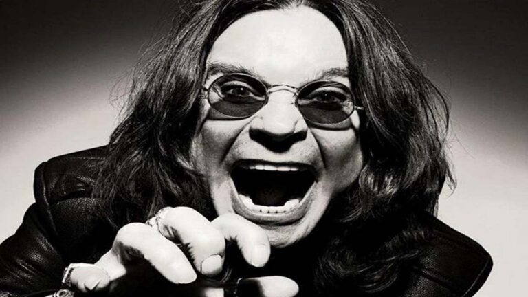 Ozzy Osbourne gritando com expressão intensa, usando óculos escuros e jaqueta de couro.