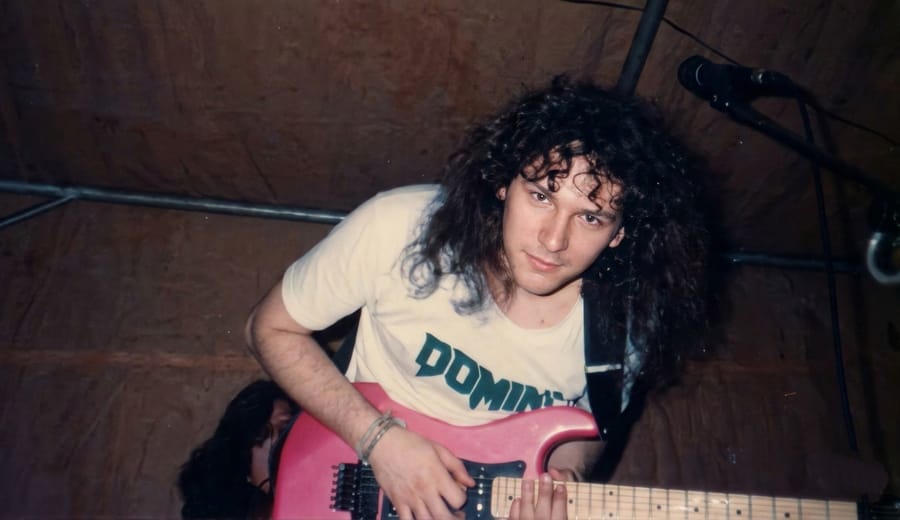 Paulo Stelzer, guitarrista da banda de rock Domini na década de 1980, tocando uma guitarra rosa durante uma apresentação ao vivo.