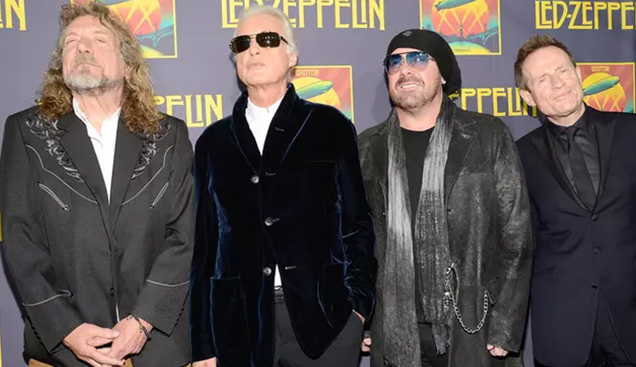 Robert Plant, Jimmy Page, Jason Bonham e John Paul Jones posam juntos em frente a um painel com o logotipo da banda Led Zeppelin durante um evento oficial.